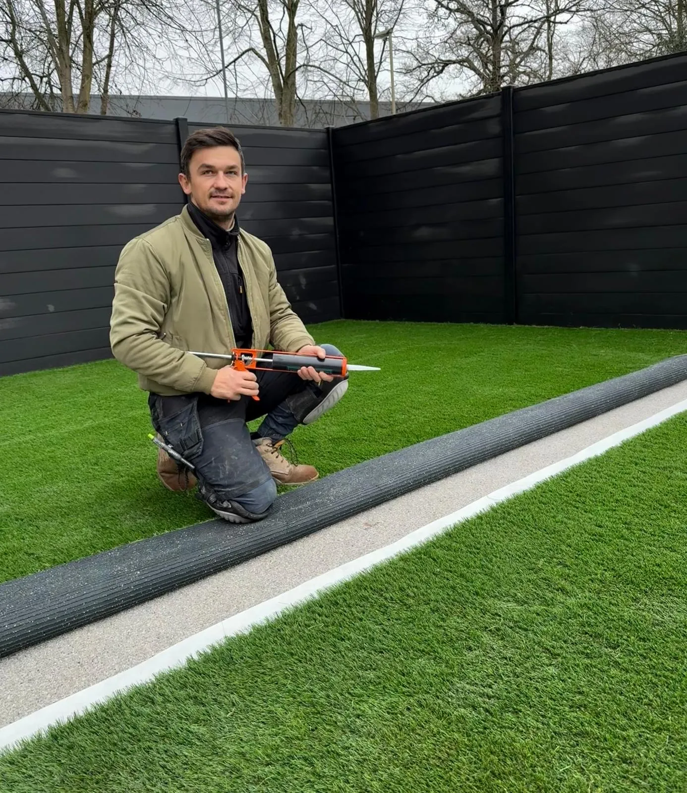 Artificial grass being installed, with a roll of turf ready to be glued at the seam