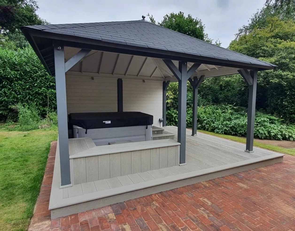 Grey composite decking with built-in seating around a hot tub, under a timber gazebo
