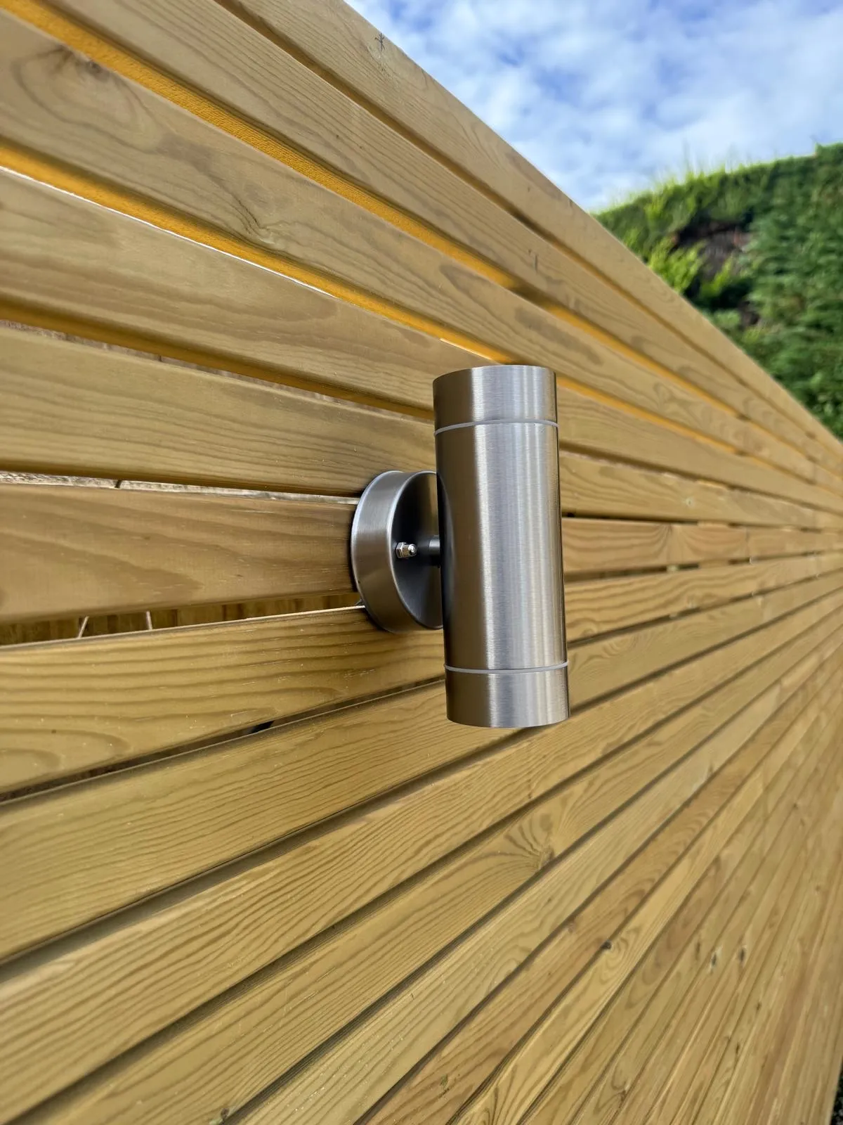 Horizontal slatted timber fence with a stainless steel wall light