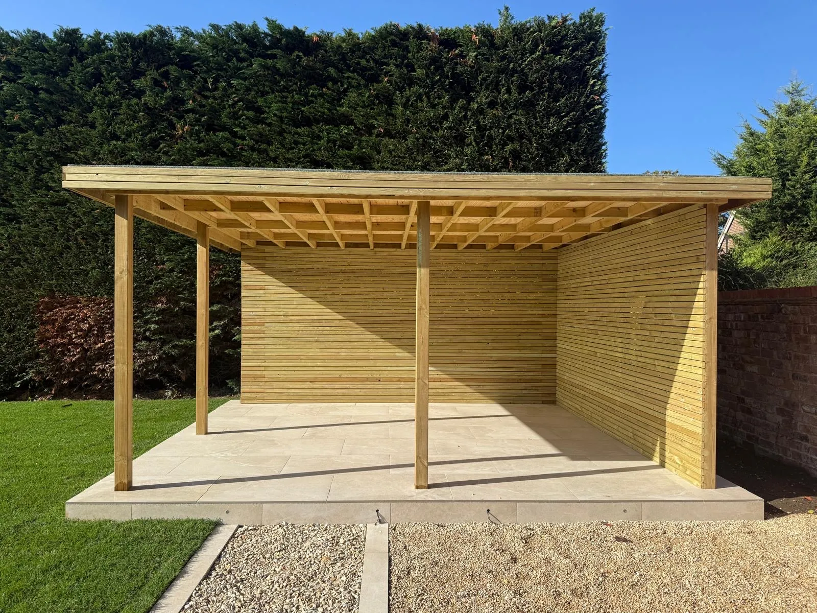 Timber garden shelter with slatted walls and a flat roof over a porcelain base